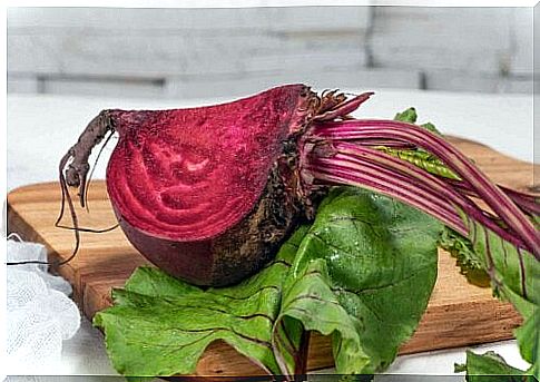 A quarter of a beetroot on a chopping board with a leaf.