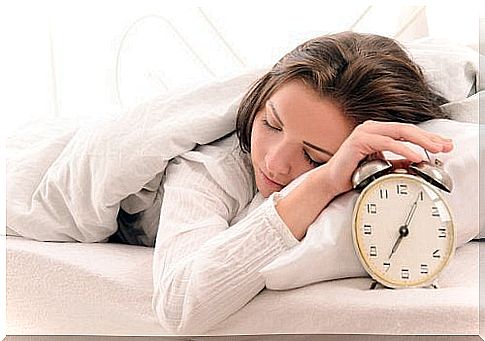 Sleeping woman with hand on an alarm clock